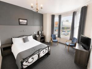 a bedroom with a bed and a television and a room at Highfield Hotel Blackpool in Blackpool