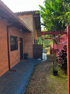 a brick house with a gate and a driveway at Tahoma Chalé Rustico Lila Prumirim in Ubatuba