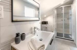a white bathroom with a sink and a shower at Chambre premium PLUME - jardin - 2p in Sainte-Geneviève-des-Bois