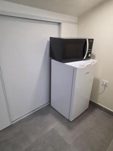 a microwave sitting on top of a refrigerator at Chambre premium PLUME - jardin - 2p in Sainte-Geneviève-des-Bois