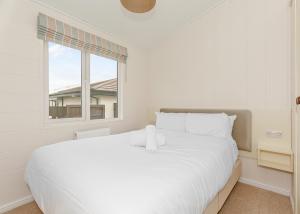 a white bedroom with a large white bed and a window at Talacre Beach Resort in Talacre