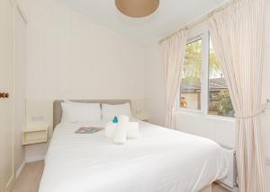 a white bedroom with a white bed and a window at Talacre Beach Resort in Talacre