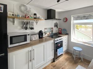 a kitchen with white cabinets and a microwave and a stove at Summers Beach View in Saint Mawes +29 photos