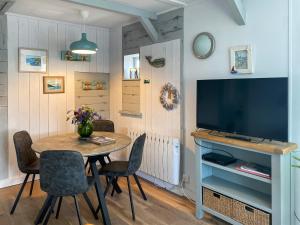 a dining room with a table and a flat screen tv at Summers Beach View in Saint Mawes