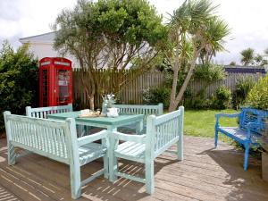 a picnic table with two benches and a telephone booth at Headland Views in Newquay