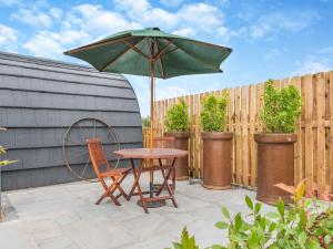 a table and chairs with an umbrella on a patio at The Warren - Uk47582 in Sutton on the Hill