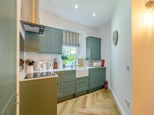 a kitchen with green cabinets and a sink at West Lodge in Perth