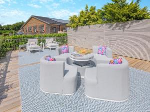 a patio with white chairs and a table on a rug at Woodlea Farm in Four Marks