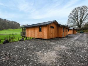 a row of wooden buildings on a gravel road at Lakeside Lodge - Uk50627 in Welshpool