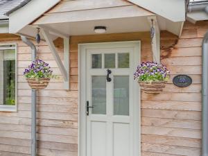 a front door of a house with two baskets of flowers at Violet Cottage in Hereford