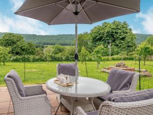 a table and chairs with an umbrella on a patio at Violet Cottage in Hereford