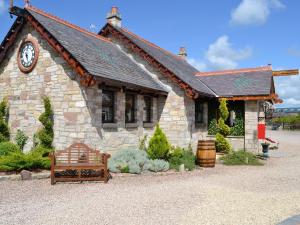 a small stone building with a clock on it at Tennox Boathouse - Ukc4438 in Kilbirnie
