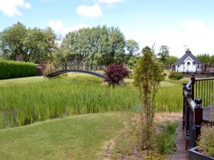 a bridge over a pond with a house in the background at Tennox Boathouse - Ukc4438 in Kilbirnie