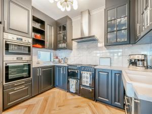 a kitchen with blue cabinets and stainless steel appliances at The Old Doctors Manor House in Whitstable +17 photos