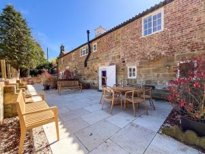 a patio with a table and chairs in front of a brick building at Coach House - Uk51830 in Great Ayton