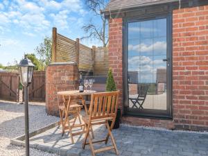 a patio with a table and chairs and a window at Fountain Front Barn - Uk45937 in Corley