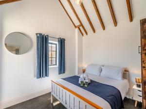 a bedroom with a bed with blue curtains and a window at Fountain Front Barn - Uk45937 in Corley +11 photos