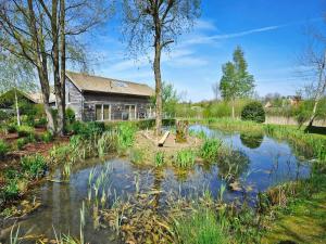 a home with a pond in front of a house at Coot Lodge in Somerford Keynes