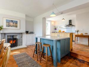 a kitchen with a blue island and a fireplace at Colveston Manor in Cranwich +23 photos