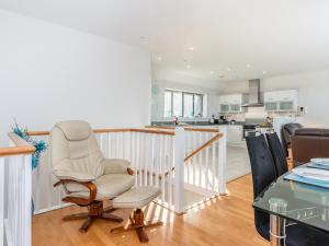 a living room with a chair and a kitchen at Sand Dunes in Westward Ho
