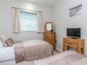 a bedroom with two beds and a flat screen tv at Sand Dunes in Westward Ho +21 photos