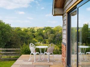 a patio with three chairs and a table with a view at The Cwtch - Os7 in Newtown