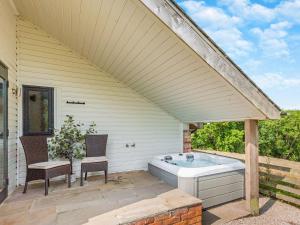 a hot tub on a patio with two chairs at The Cwtch - Os7 in Newtown