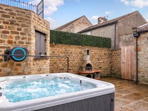 a large bath tub in a courtyard with a brick wall at Ghyll Cottage - Uk51667 in Leyburn
