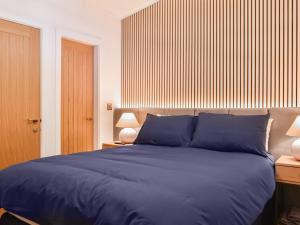 a bedroom with a large blue bed with two lamps at Willow Lodge in Ingleton