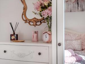 a shelf with a vase of pink flowers and a mirror at West House in Wooler +8 photos