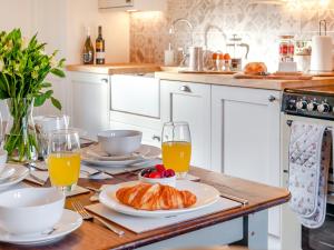 a kitchen with a table with croissants and orange juice at West House in Wooler