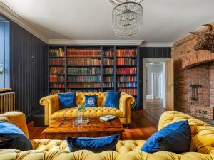 a living room with a yellow couch and bookshelves at Killerby Old Hall - Uk47711 in Cayton