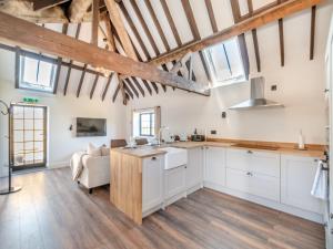 a kitchen with white cabinets and wooden floors and windows at Corley Rocks Barn - Uk45939 in Corley