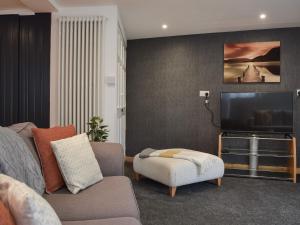 a living room with a couch and a flat screen tv at The Spinney in Carterton