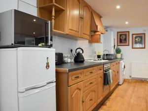 a kitchen with wooden cabinets and a white refrigerator at The Spinney in Carterton +9 photos