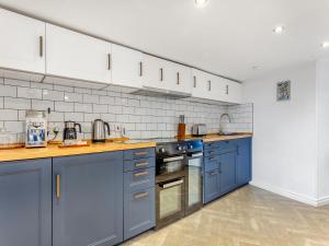 a kitchen with blue cabinets and white appliances at Roggle Roich in Hilton of Cadboll