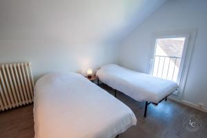 two beds in a room with a window at Maison Le Damier - Proche Center Parcs et Lamotte Beuvron - 3 chambres in La Ferté-Saint-Aubin