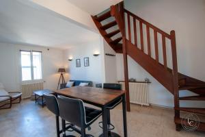 a living room with a wooden table and a staircase at Maison Le Damier - Proche Center Parcs et Lamotte Beuvron - 3 chambres in La Ferté-Saint-Aubin