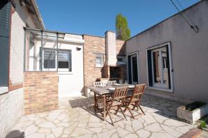 a patio with a wooden table and chairs at Maison Le Damier - Proche Center Parcs et Lamotte Beuvron - 3 chambres in La Ferté-Saint-Aubin