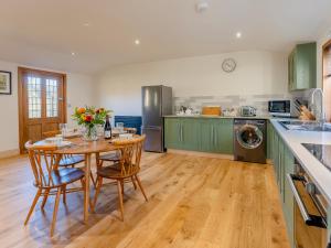 a kitchen with green cabinets and a table with flowers on it at Bluebell Lodge-Uk32958 in Molash