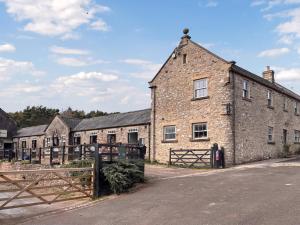 an old brick building with a fence in front of it at Stable Cottage - Uk51669 in Leyburn