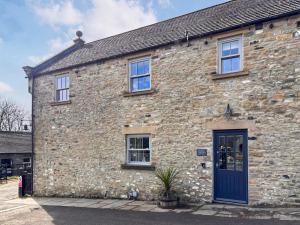 an old stone building with a blue door at Stable Cottage - Uk51669 in Leyburn