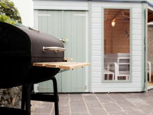a grill sitting on a patio with a shed at Llywnfor in Morfa Nefyn