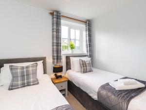 two beds in a room with a window at Dovecote House-Uk30233 in Cayton