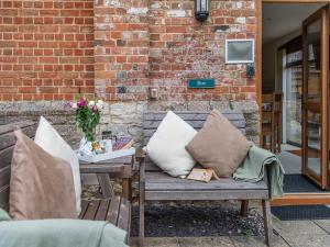 a wooden bench with pillows on a patio at Byre - Uk49899 in Blandford Forum