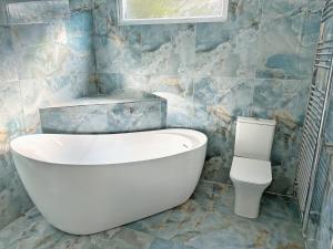 a bathroom with a white tub and a toilet at Ashtree Hideaway in Brandon