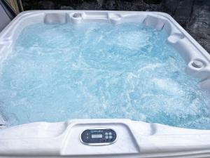 a bath tub filled with blue water with a remote control at Ashtree Hideaway in Brandon +5 photos