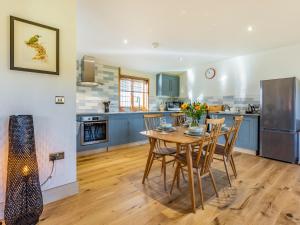 a kitchen with a wooden table with chairs and a refrigerator at Snowdrop Lodge -Uk32959 in Molash