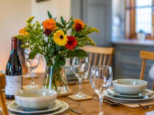 a table with a vase of flowers and a bottle of wine at Snowdrop Lodge -Uk32959 in Molash