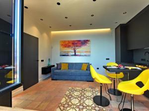 a living room with a blue couch and yellow chairs at Mira Suite in Vietri sul Mare